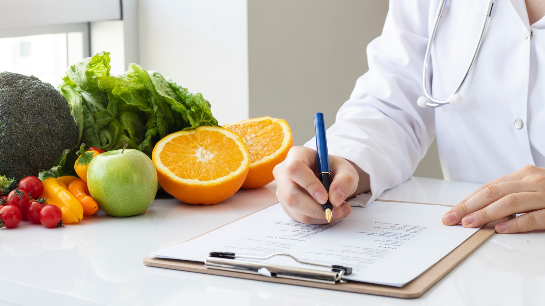 野菜と果物を前に、記録を書き込む医師